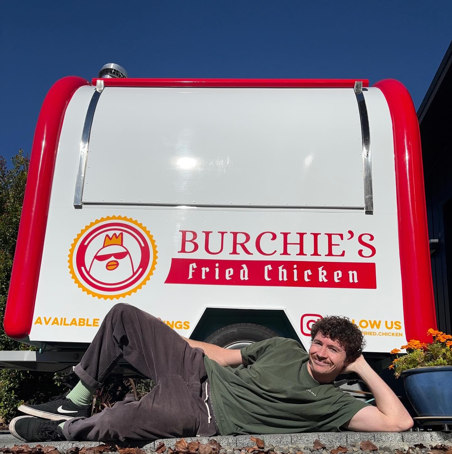 Burchie lying on the ground in front of the newly-wrapped Burchie's truck