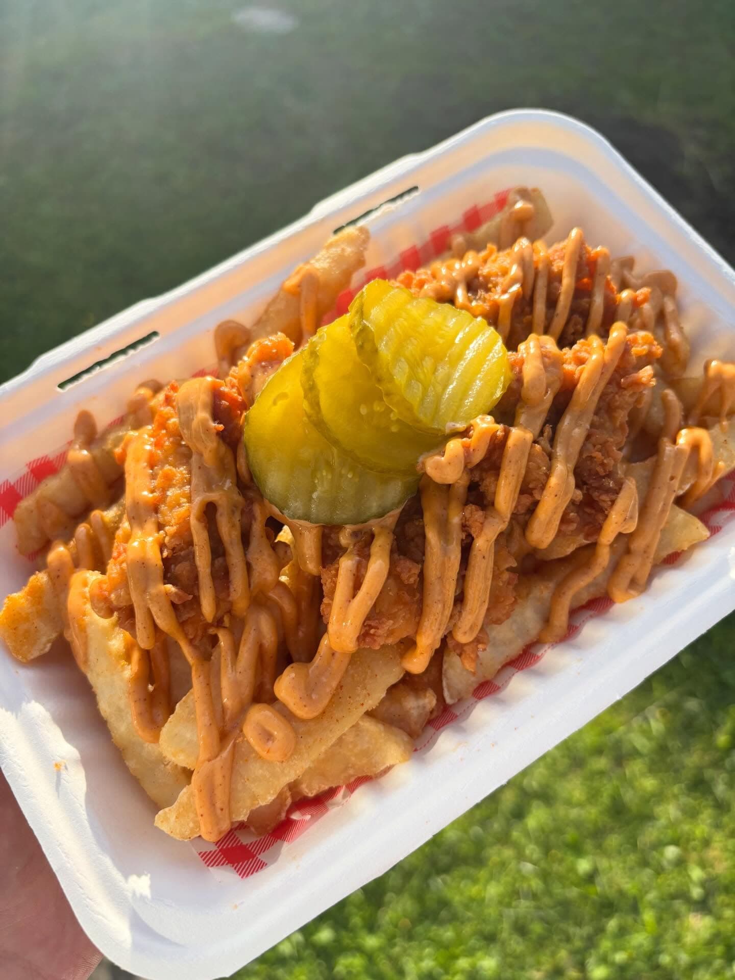 Burchie's loaded fries topped with fried chicken, sauce, and pickles